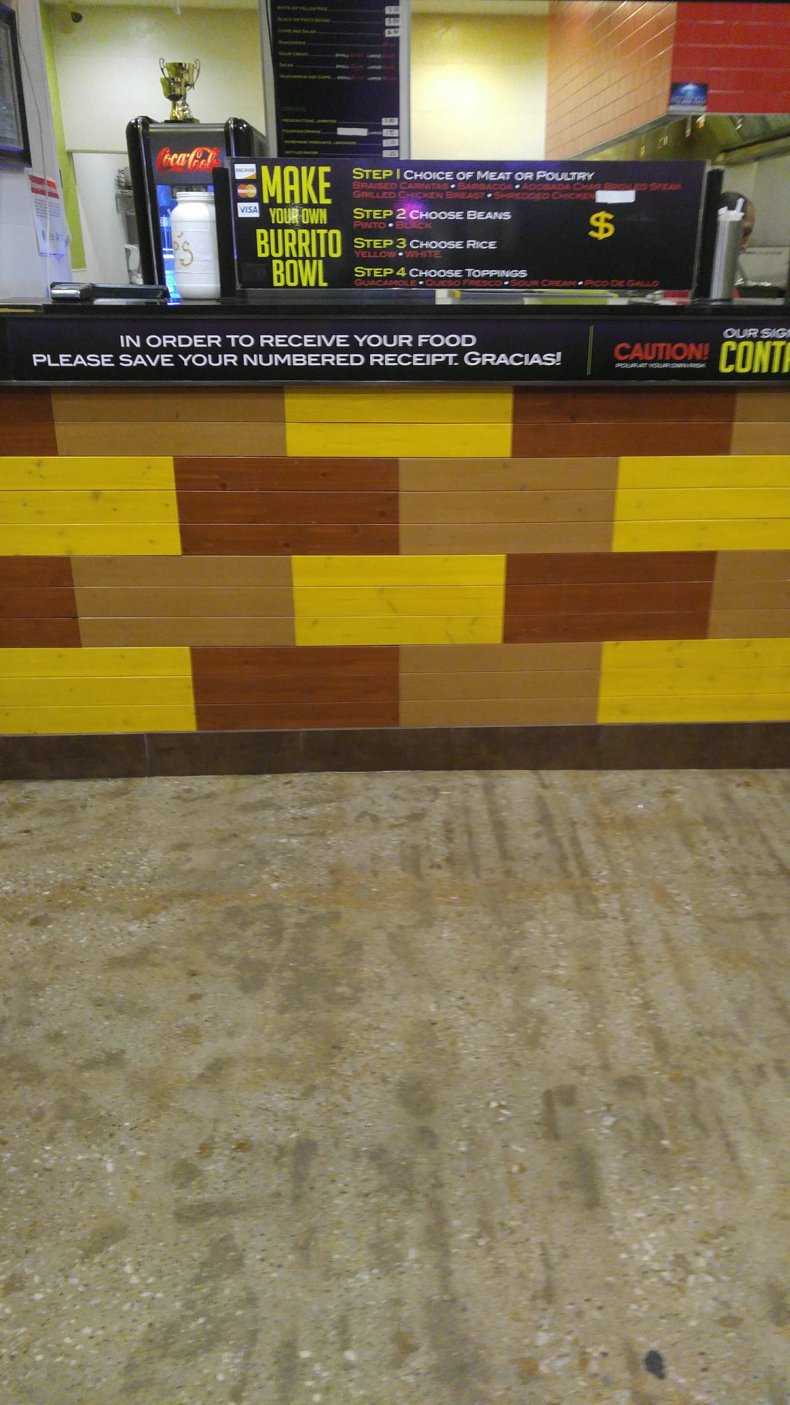 Pickup counter with the make-your-own burrito bowl sign and numbered-receipt notice