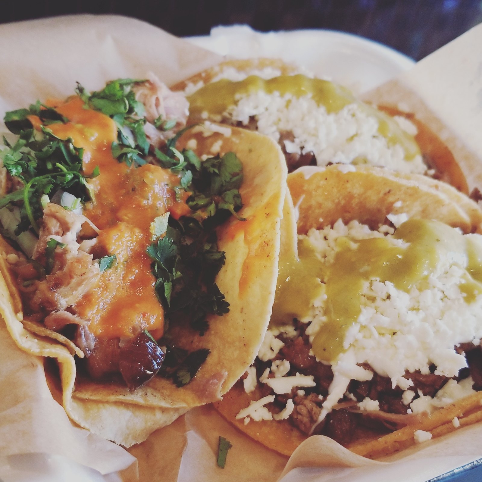 Assorted tacos with cilantro, salsa, and queso fresco